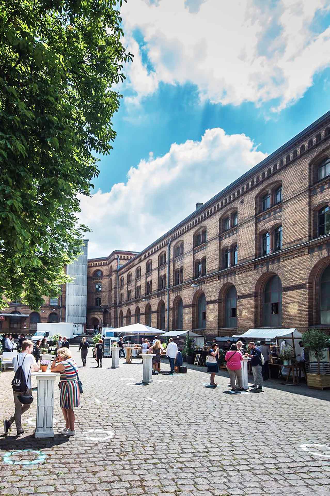 Blick auf den Aussenbereich des Magazin in der Heeresbäckerei blauer Himmel Personen Foodtrucks