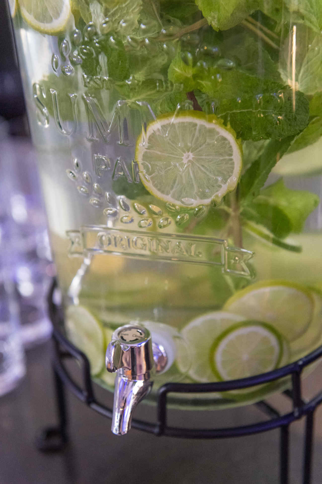 Nahaufnahme eines Wasserspenders voller Limettenscheiben und Minze