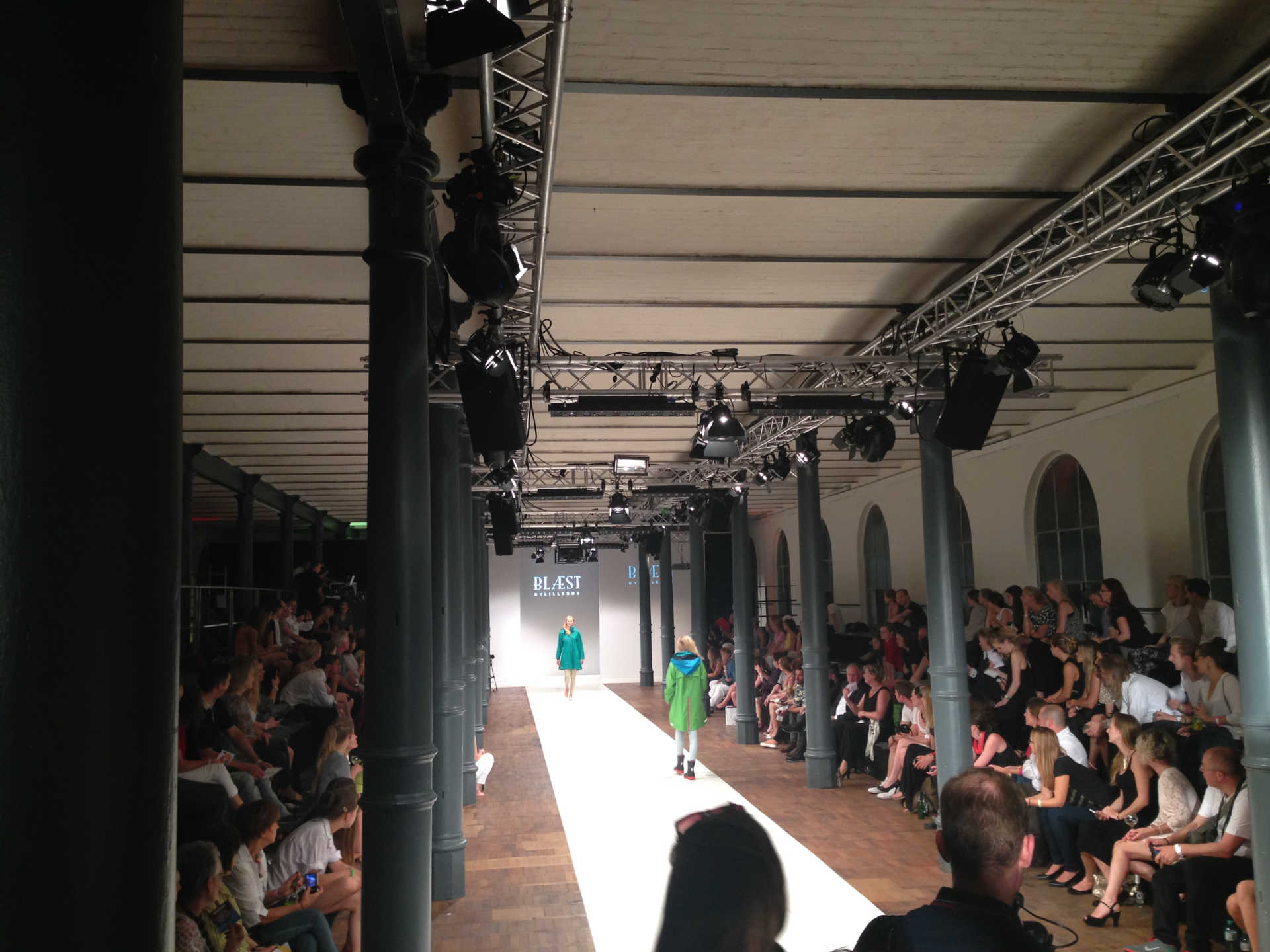 Schwarz-weiß Foto von Modenshow mit Model am Ende des Laufstegs.