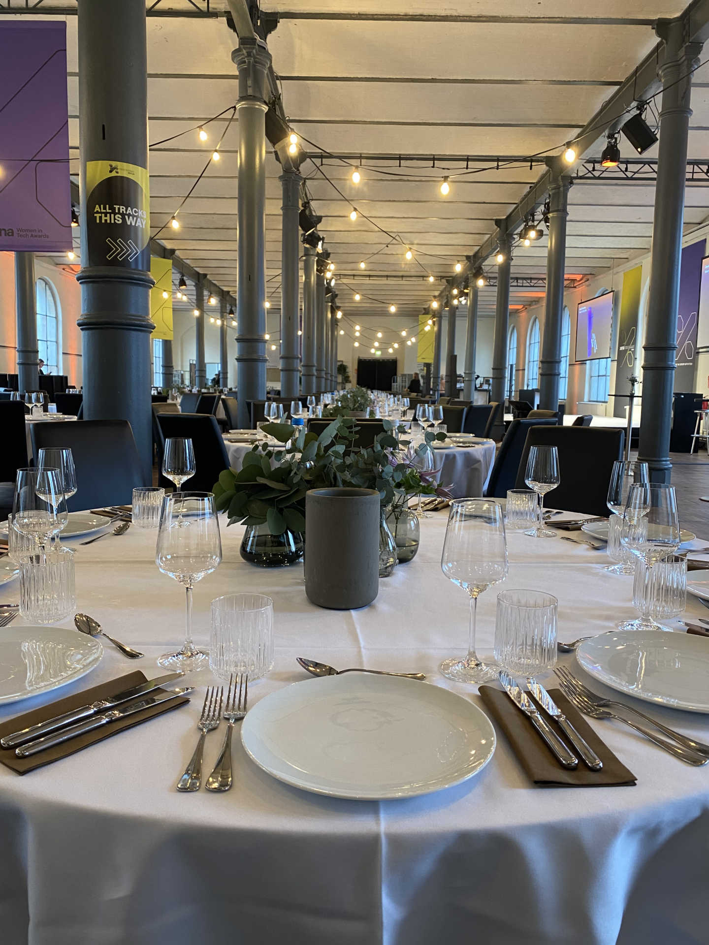 Festsaal mit runden gedeckten Dinnertischen mit weißen Tischdecken