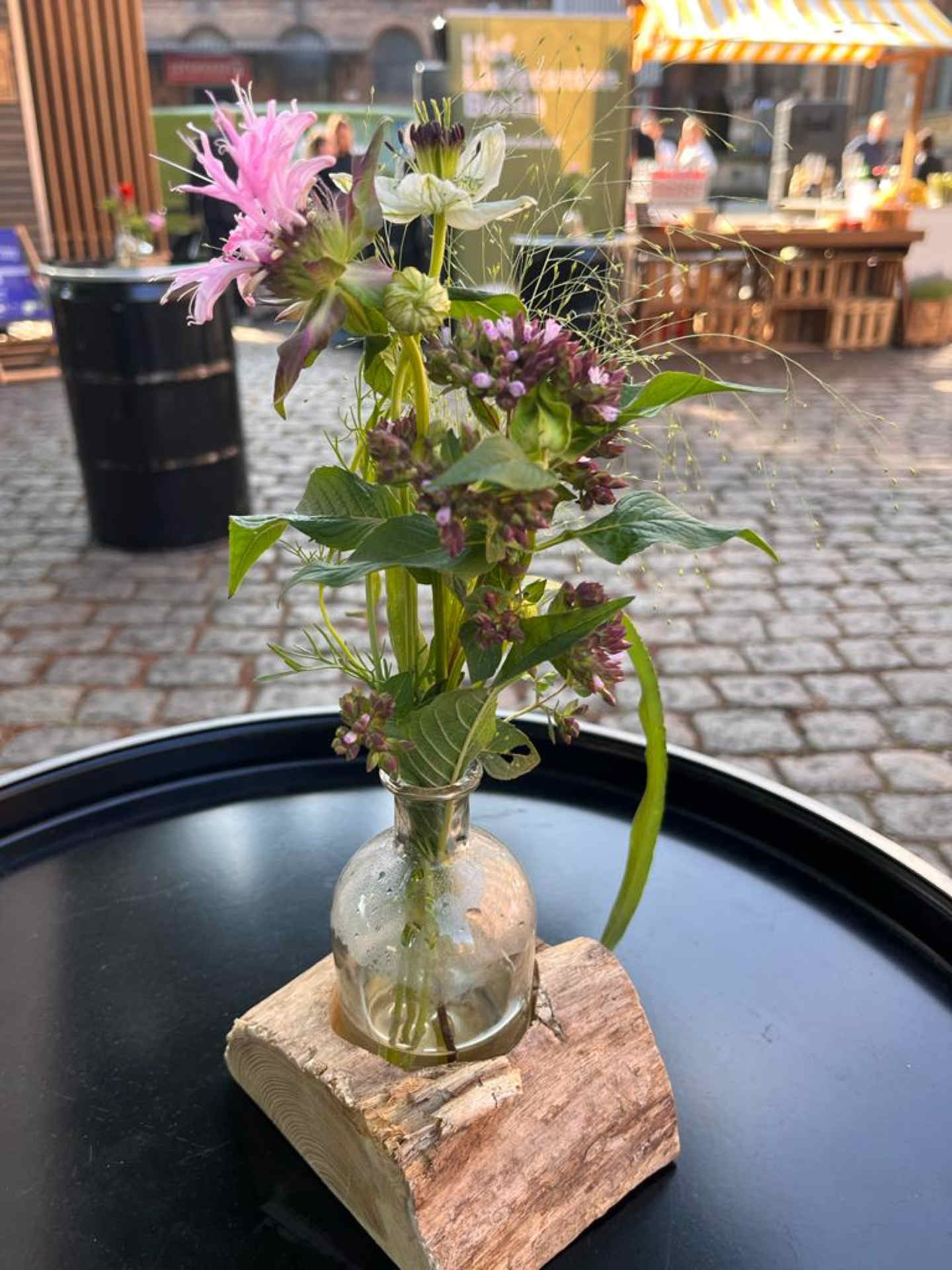 Draußen im Sommer blickt man auf einen Stehtisch mit Blumendekoration