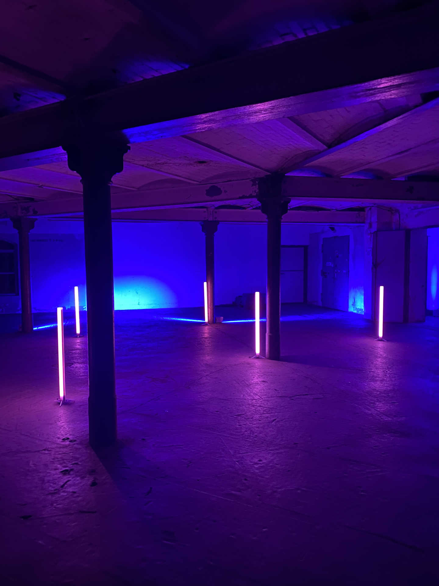 Industrieller Raum mit Säulen und stehenden Neonröhren.