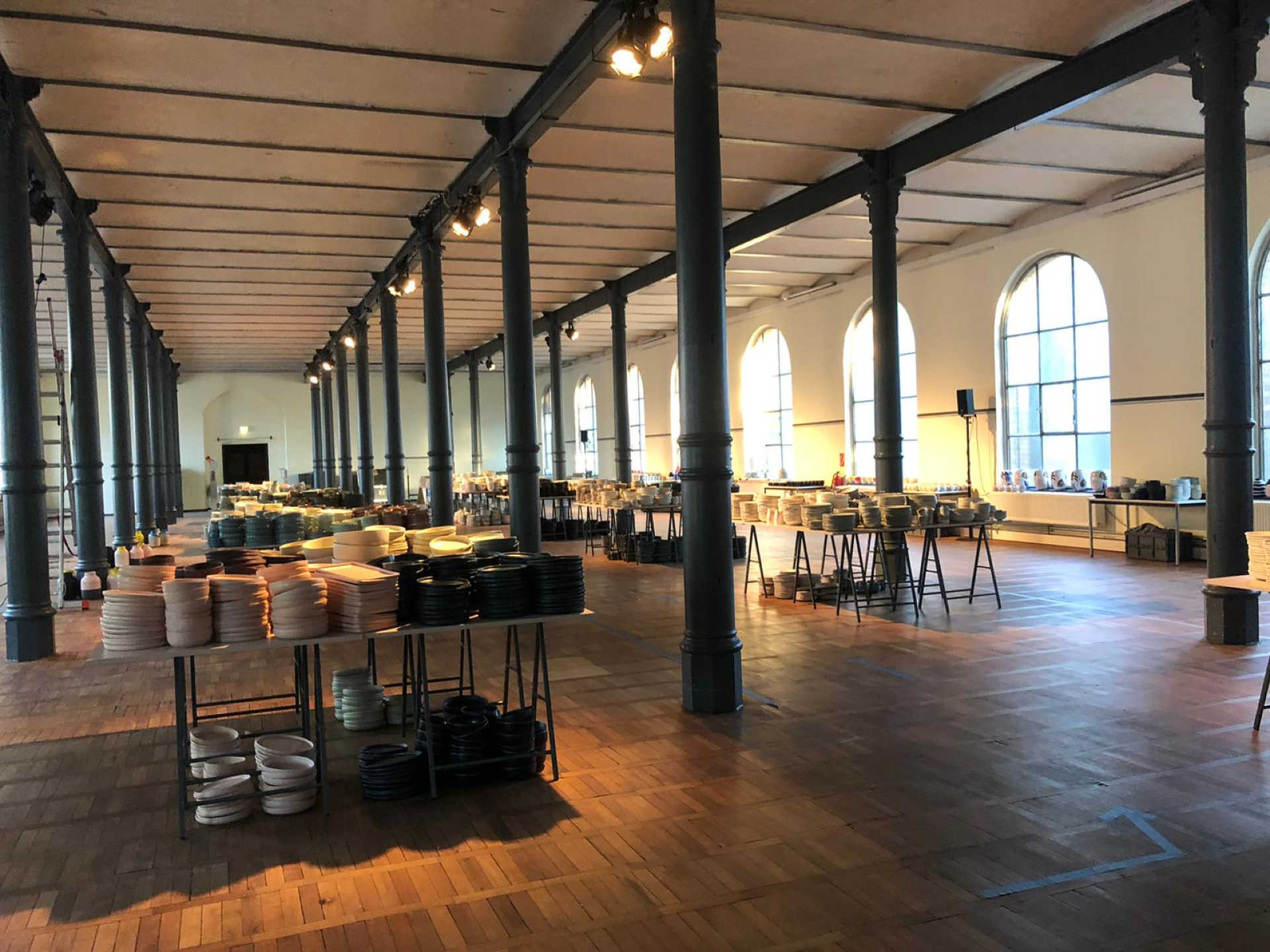 Große Menge an gestapeltem Geschirr auf Produkttischen.