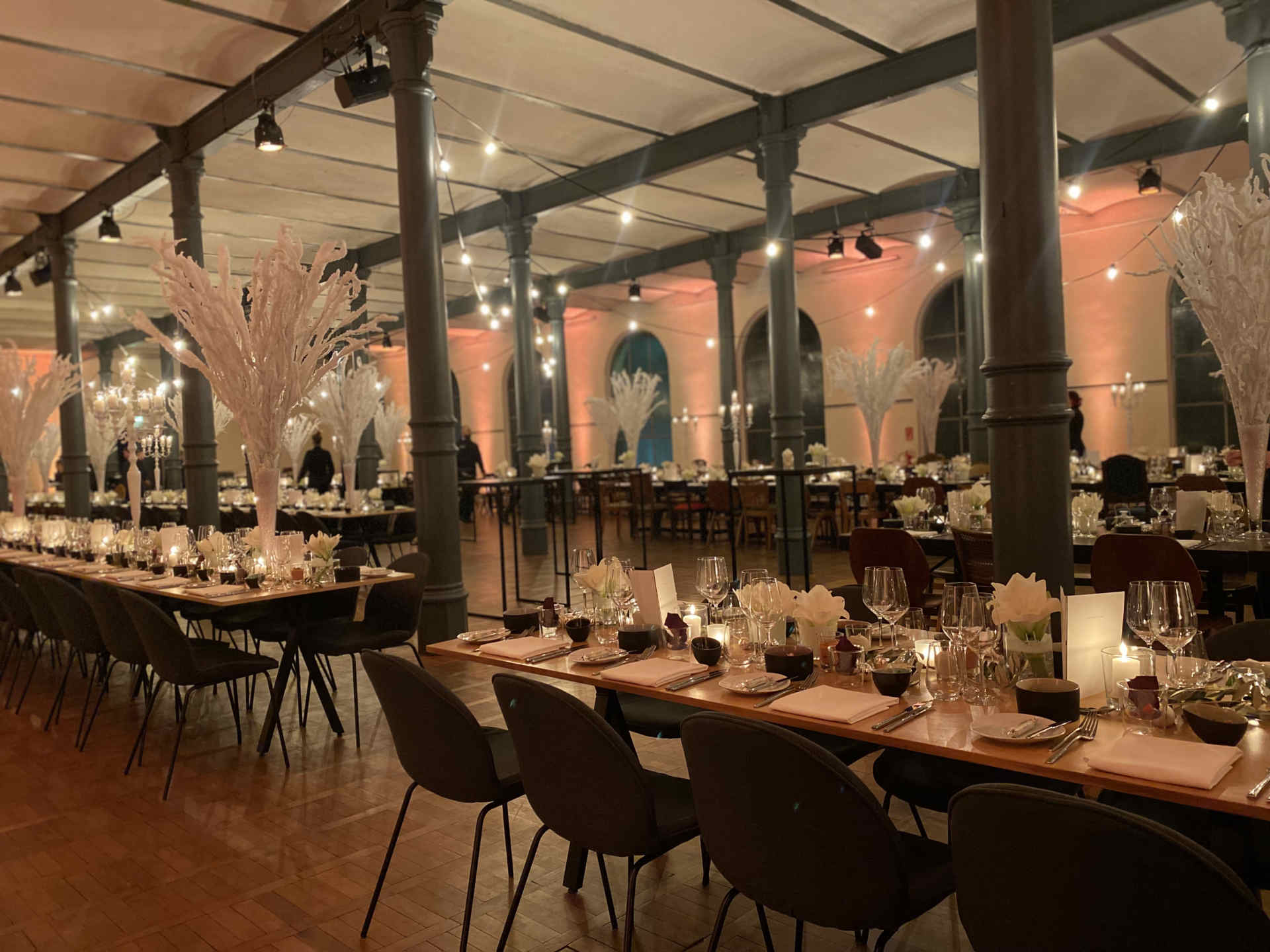 Saal mit vielen, üppig gedeckten Tafeln und festlicher Dekoration am Abend