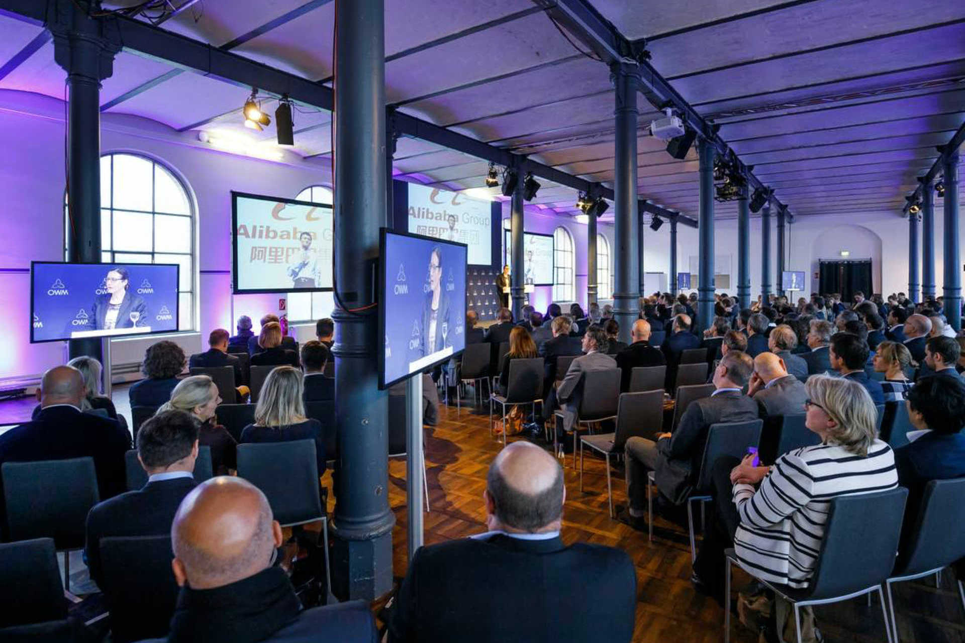Großer Saal mit vielen Menschen in Konferenzbestuhlung und vielen Bildschirmen