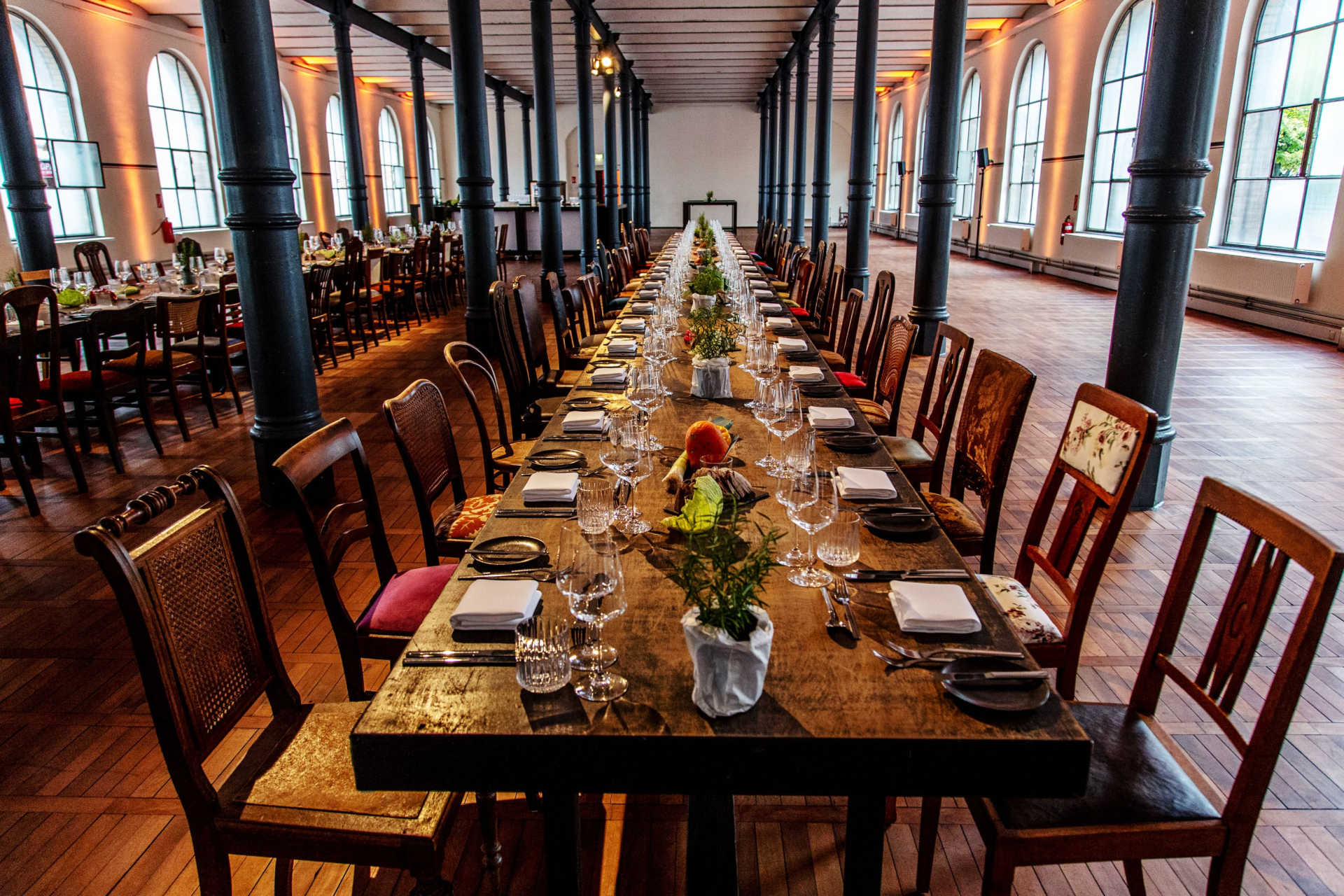 Lange gedeckte Holztafel in großem Saal