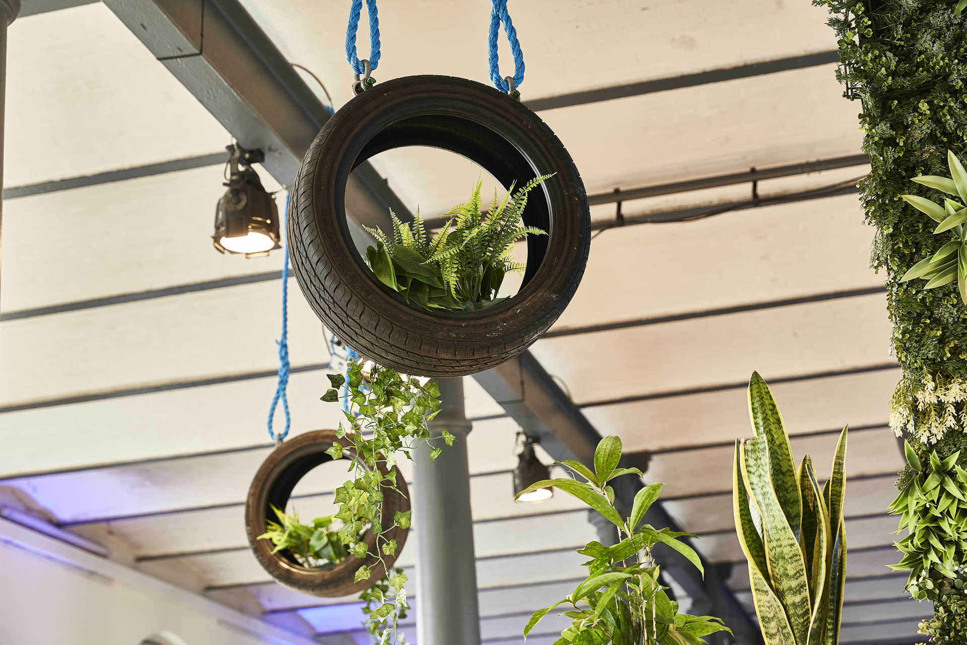 Hängende Deckendekoration mit Autoreifen und Grünpflanzen.