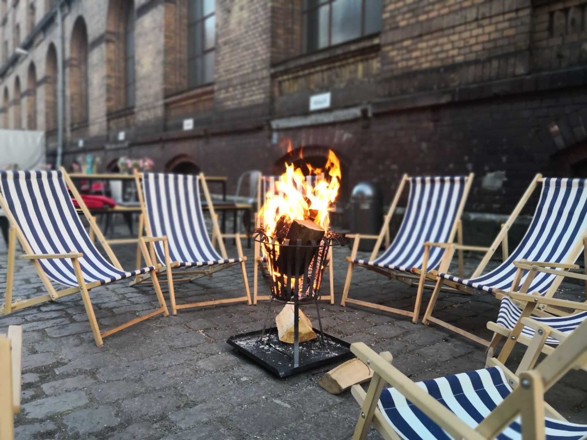 Gestreifte Liegestühle im Kreis mit Feuerschale in der Mitte