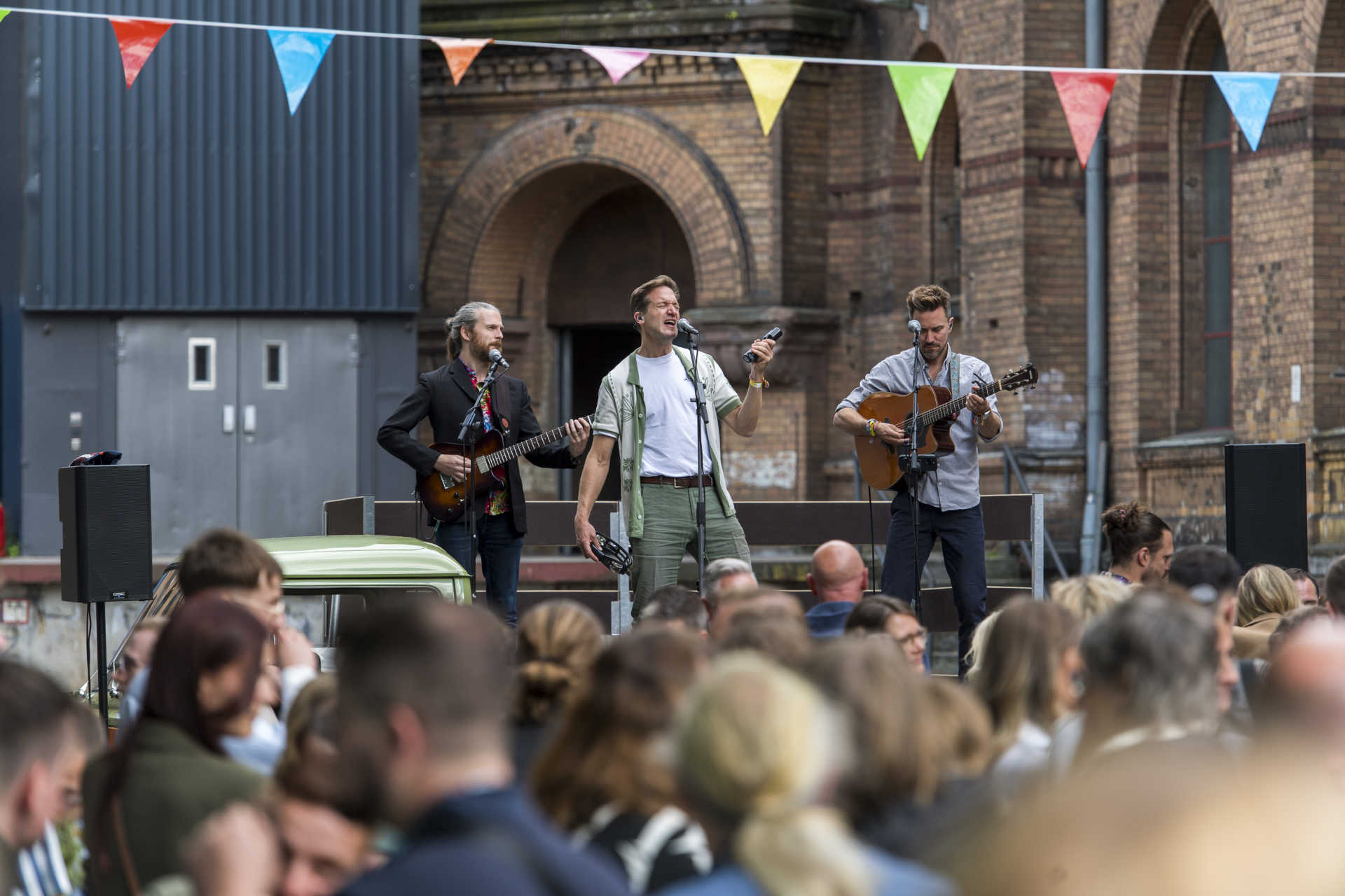 Liveband spielt outdoor vor Menschenmenge mit Wimpelkette