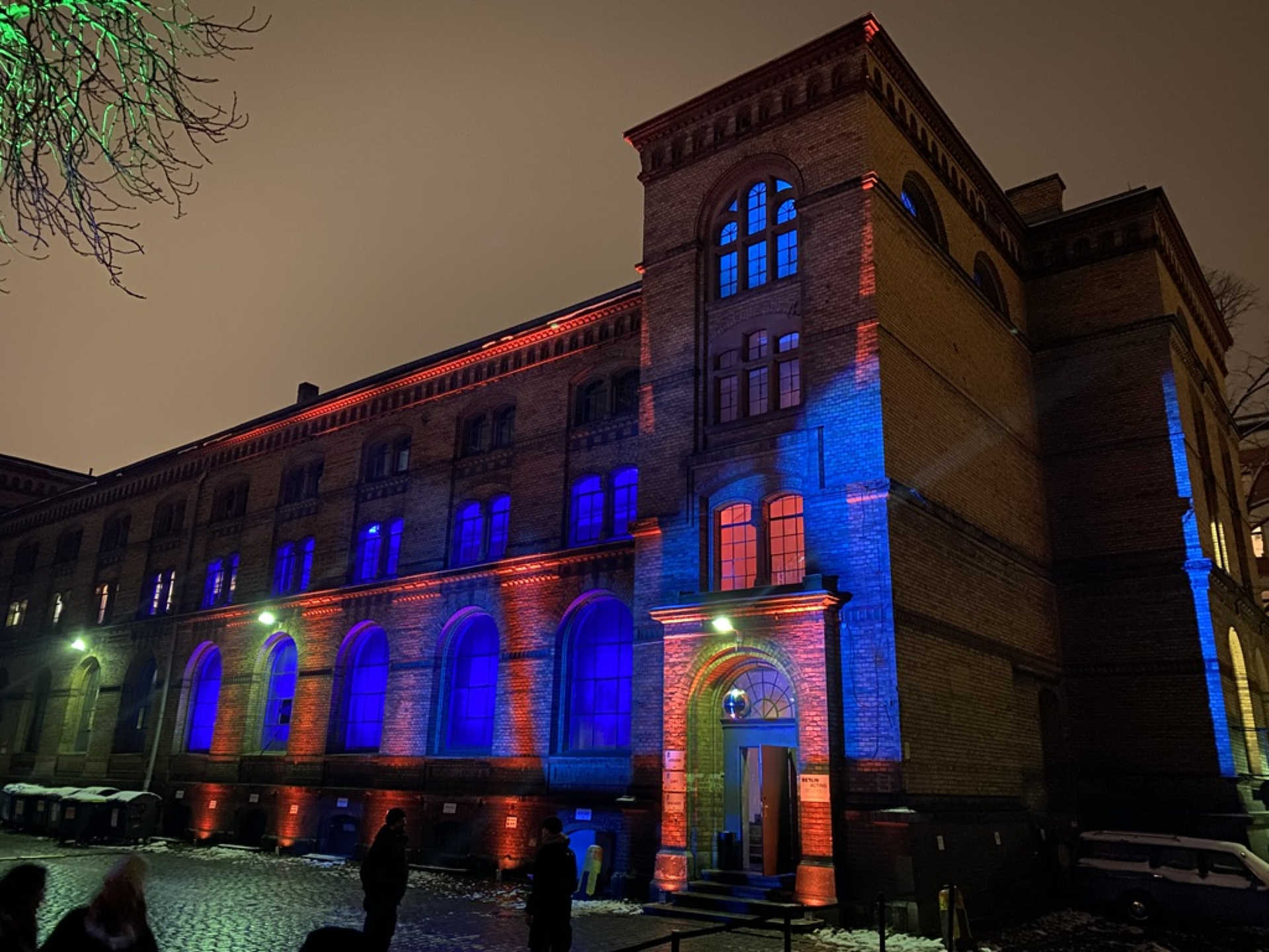 Großes Backsteingebäude mit blau-roter Beleuchtung im Dunkeln