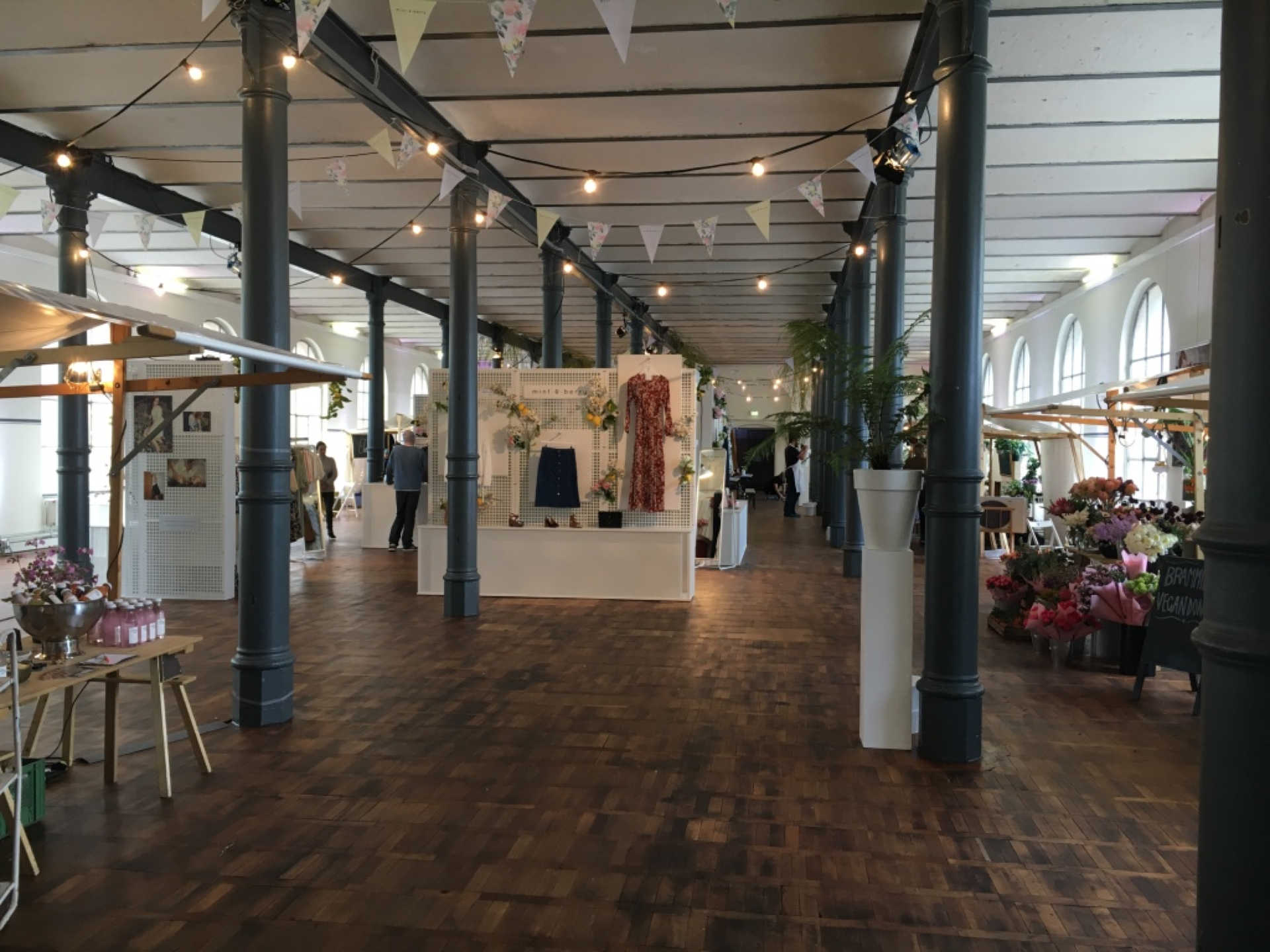 Großer Saal mit Blumenständen und Produktpräsentationen.