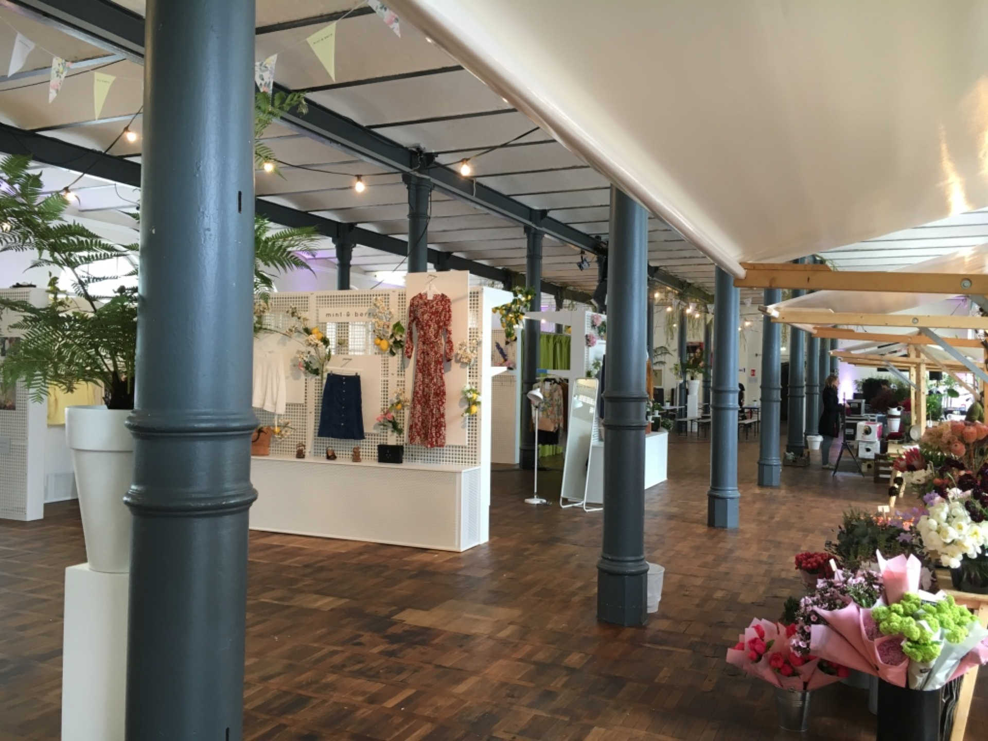 Industrieller Saal mit Marktständen und Ausstellungsstationen.